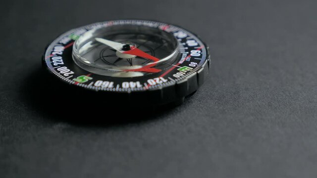 Extreme close up of a transparent modern compas on black background. Concept of travel, adventure, expedition 4k
