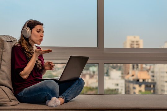 Woman sending air kiss during video call by laptop