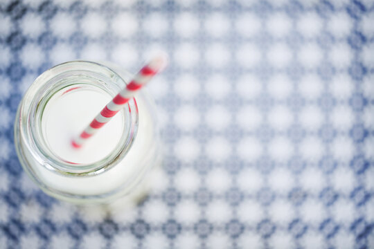 Red and white striped straw in milk glass on patterned tray