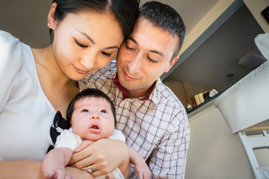 Happy interracial family with newborn baby girl at home