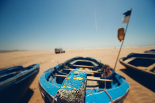 A wooden boat docked on a dry beach waiting for high tide