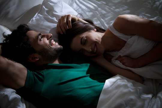 Young couple talking and laughing in bed before sleep.