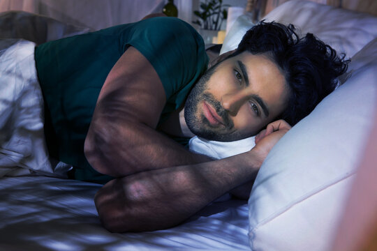 Young Restless Man Lying In Bed At Night.