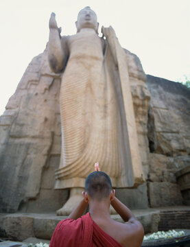 Buddhist Monk praying at the Avukana Buddha. Sri Lanka