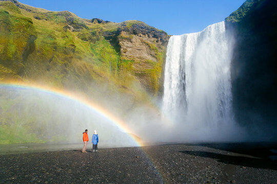 Iceland, Skogar, Skogafoss Falls, southern Iceland. Visitors standing in front of the Falls. Skogafoss is one of 20 waterfalls found along the Skogar River. The waterfall is 60 meters high.