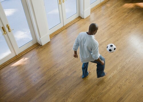 Man Kicking Soccer Ball At Home