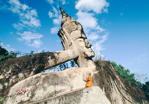 Laos, Vientiane, monk praying to Statue of Buddha in Xieng Khuan Buddha Park, Vientiane Province, Laos, Indochina, Southeast Asia, Asia