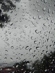 water drops on glass in a cloudy day with  some trees in the back 