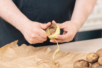 Man peeling potatoes in his kitchen