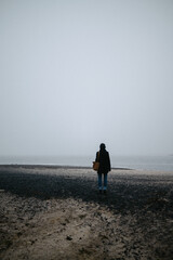 the girl walks along the foggy seashore