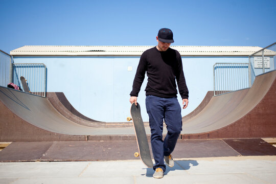 Young man walking away from a halfpipe after a skateboarding session