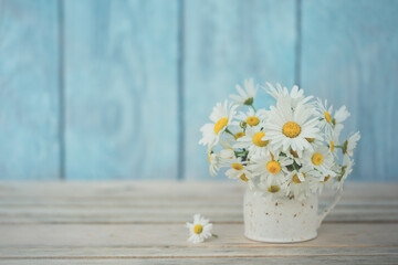 Bouquet of chamomile (Matricaria) on an old blue wooden background. Like postcard texture, background, concept and idea.