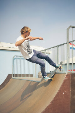 Young man balancing on a rail with his skateboard