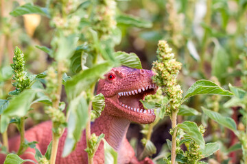 Toy dinosaur in the thicket imitates the natural environment. Toy for children.