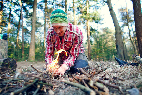 Man starting a camp fire in a forest
