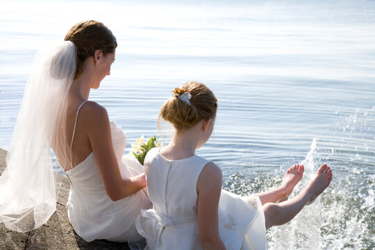 Bride and Flower Girl having fun by the sea.