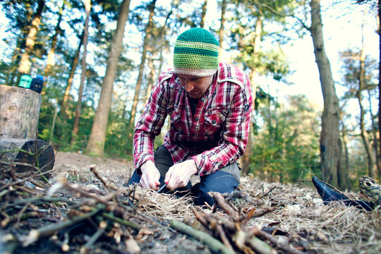 Man starting a camp fire in a forest