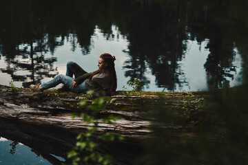 sitting girl on the shore of the lake. loneliness reflection concept of enjoyment of travel and recreation