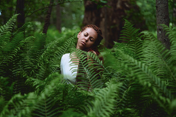 Naklejka premium girl in the forest in the thickets of fern. nature health concept cosmetics and inspiration