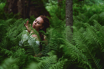 Naklejka premium girl in the forest in the thickets of fern. nature health concept cosmetics and inspiration