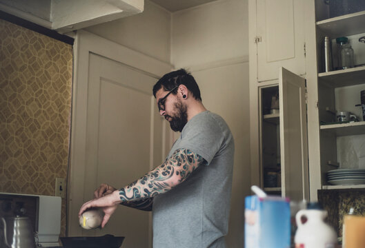 A handsome tattoo'd man cooks in his kitchen
