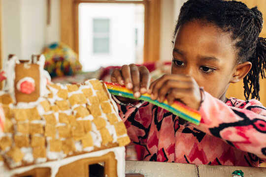 African American girl putting candy on a gingerbread house