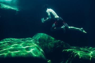 Man running underwater with a large rock in a mountain stream rock pool