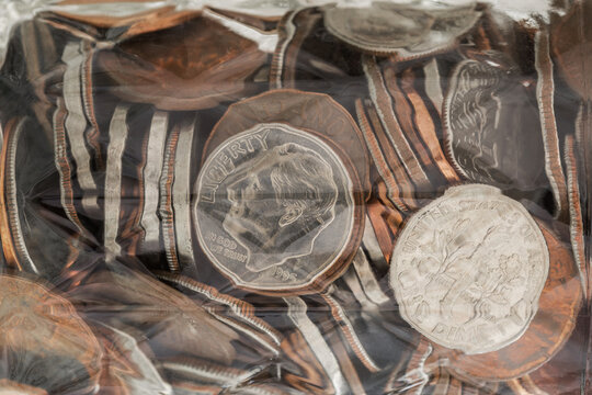 Abstract macro showing glass jelly jar filled with various coins.