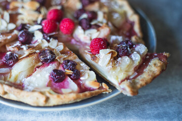 Galette with pear, berries, almonds on grey table shot from above