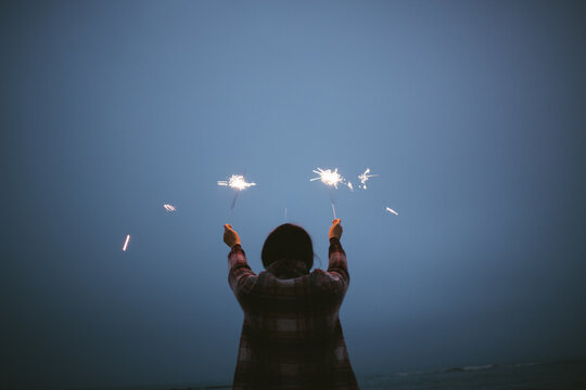 Girl on the beach holding sparkle sticks