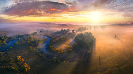 Mystical morning river, the sun's rays shine through the fog.
