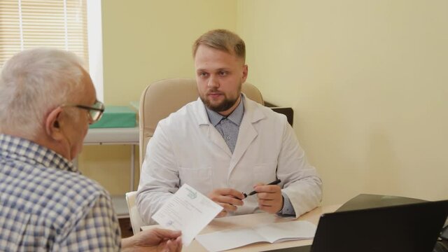 Male neurologist prescribes a prescription for an elderly patient.