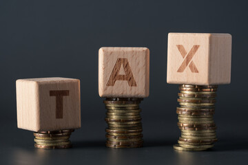 Tax concept, wooden block with text on stacked coins
