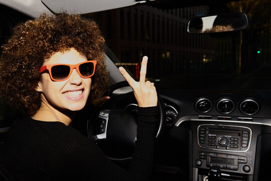 Afro young woman in sunglasses driving a car