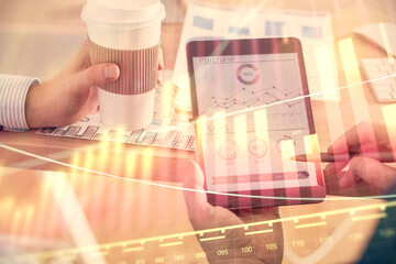 Double exposure of man's hands holding and using a phone and financial chart drawing. Market...
