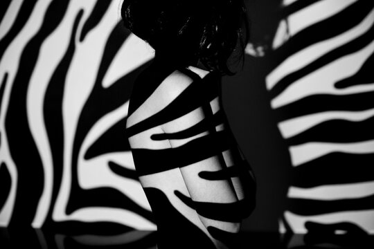 Black and white portrait of a woman with zebra stripe shadow on her body
