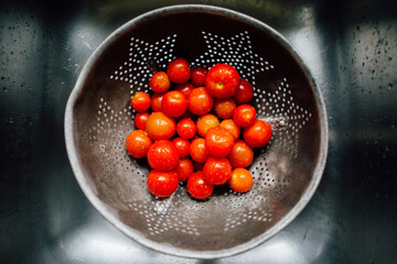 cherry tomatoes being washed in a colandar