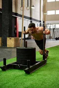 Man pushing weighted sled in a gym