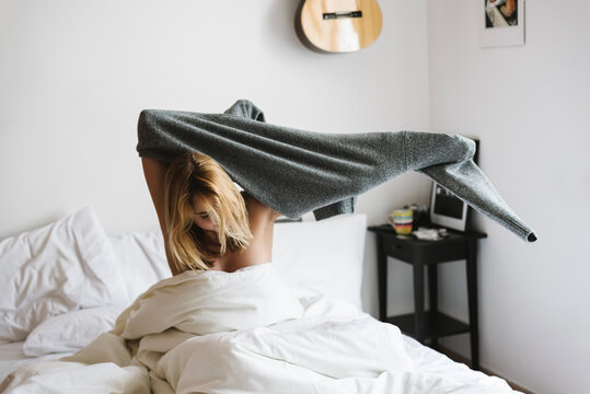 Young woman is wearing a sweater in the bed