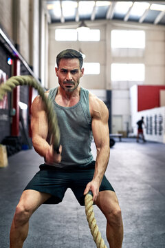 Man working out with exercise ropes in a gym