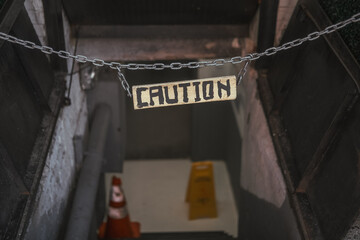 Caution sign board hanging above the basement stairs on the street