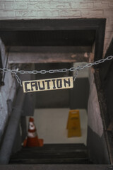 Caution sign board hanging above the basement stairs on the street