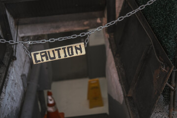 Caution sign board hanging above the basement stairs on the street