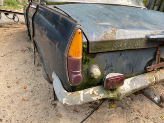 Ausschnitt Hecklicht in orange und rot, chrom Sto&szlig;stang bemost, eines verwitterter Oldtimer schwarz verrostet 