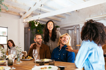Diverse friends chatting happily at dinner table on holiday