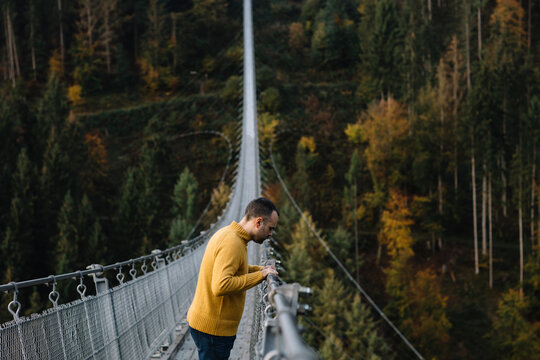 Fototapeta Man standing on a suspension bridge and looking down