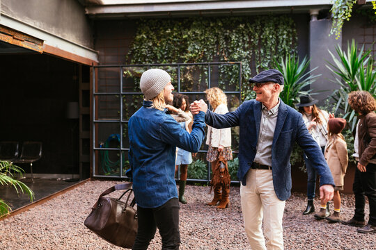 Father And Son Greeting Each Other In Yard Of Family House