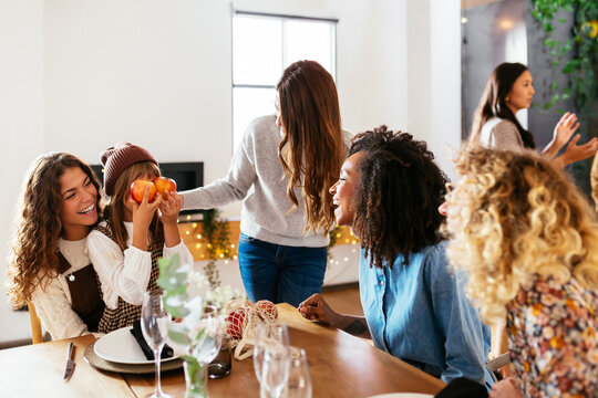 Cheerful women looking at funny girl during family holiday