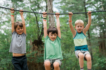Three monkey boys playing on tire swings at summer camp