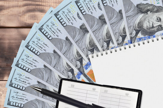 100 US dollars bills fan and notepad with contact book and black pen. Concept of financial planning and business strategy